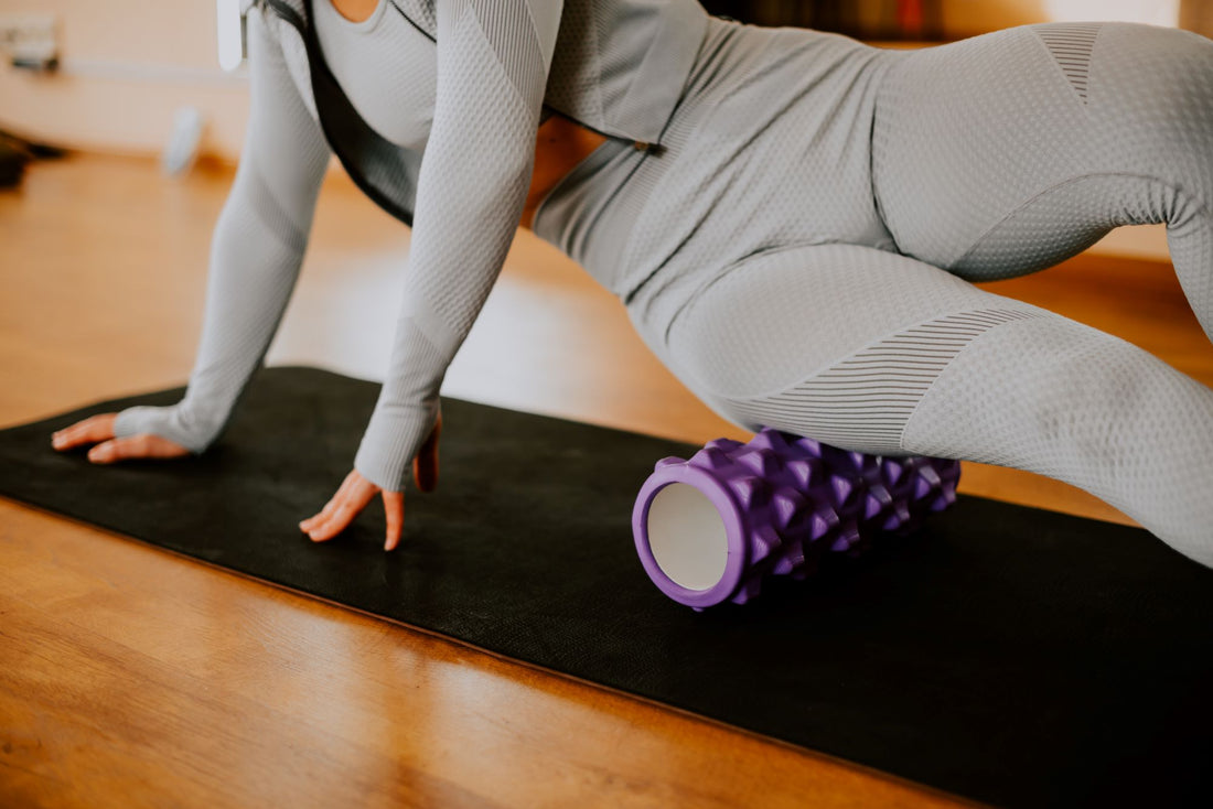 Woman Foam Rolling using a ridged roller on a yoga mat