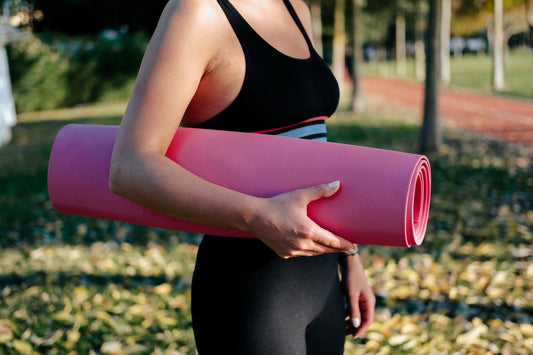 How to choose the best yoga mat, factors to consider, woman holding a pink yoga mat