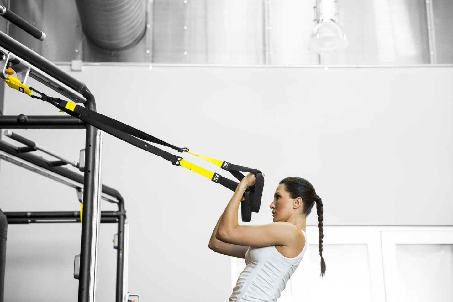woman using TRX Commercial Suspension Trainer Strap for home bodyweight workouts.